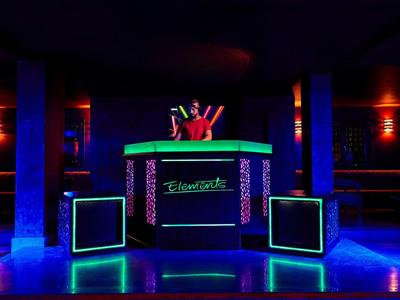 Bunte DJ-Kabine mit Neonlichtern und Lautsprechern in dunklem Clubambiente.