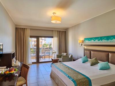 Hell eingerichtetes Hotelzimmer mit Doppelbett, Balkon, Schreibtisch und Sitzbereich.