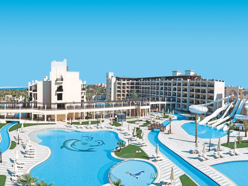 Große Hotelanlage mit mehreren Swimmingpools, Wasserrutschen und Liegebereichen bei klarem Himmel.