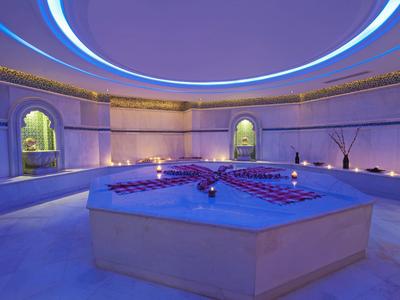 Runder Raum mit blau beleuchtetem Badebecken und weichen Lichtelementen an den Wänden.