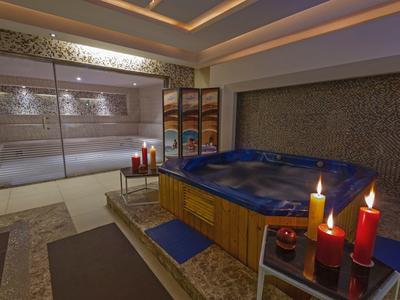 Moderner Spa-Raum mit blauer Whirlwanne, Kerzenlicht und gefliesten Wänden.