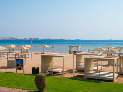 Spiaggia con lettini, ombrelloni e vista sul mare blu sotto un cielo sereno.