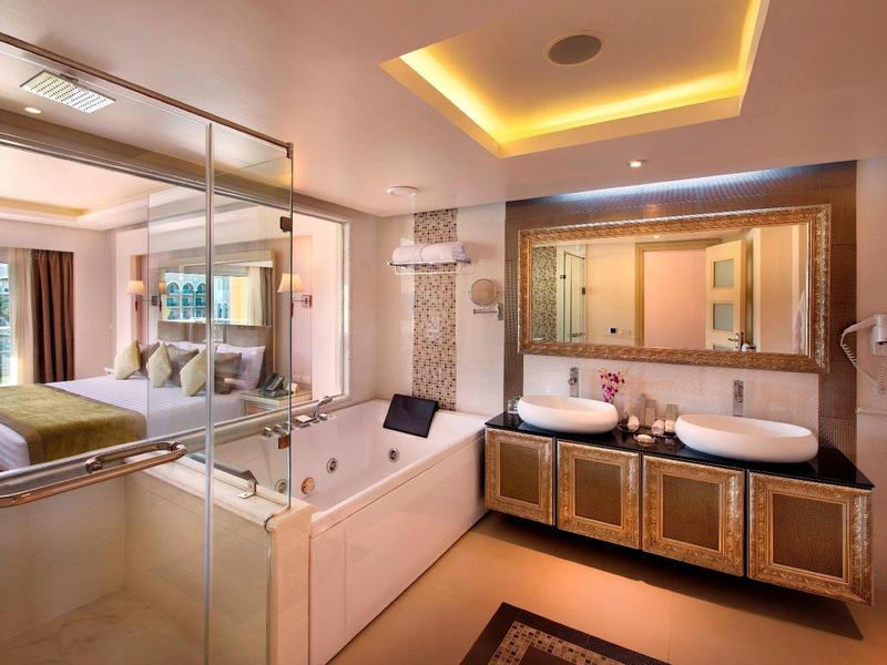 Modernes Badezimmer mit Badewanne, Doppelwaschbecken und großer Glasdusche, warm beleuchtet.