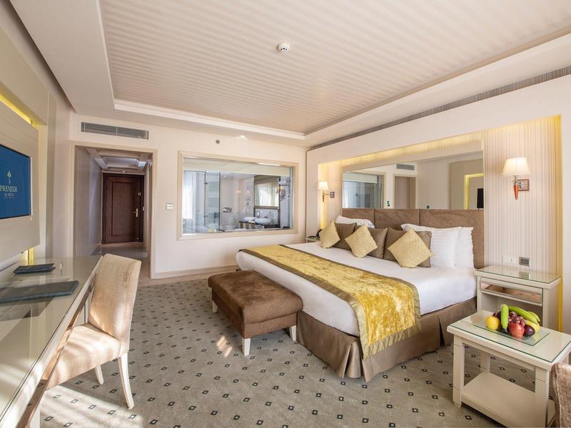 Modern eingerichtetes Hotelzimmer mit großem Bett, TV, Schreibtisch und sitzbarer Couch.