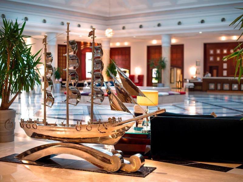 Modell eines großen Segelschiffs aus Holz, dekorativ im hellen Hotel-Lobbybereich mit Pflanzen.