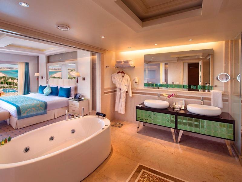 Modern eingerichtetes Hotelzimmer mit Badewanne, Doppelwaschbecken und großzügigem Schlafzimmer.