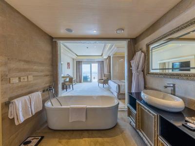 Luxuriöses Badezimmer mit freistehender Badewanne, großem Spiegel und Blick ins helle Wohnzimmer.