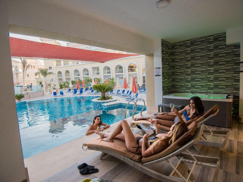 Deux femmes se détendent sur des transats à côté d'une piscine d'hôtel