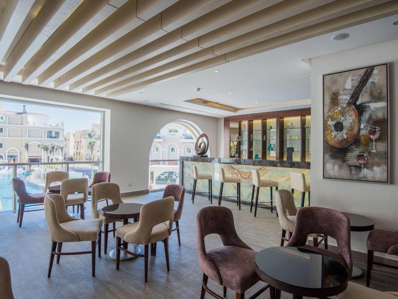 Bar moderne avec sièges, tables et vue sur l'eau et les bâtiments.