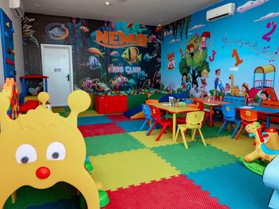 Bunter Kinderspielraum mit Matten, Tischen, Stühlen und Themenspielzeug im Hotel.