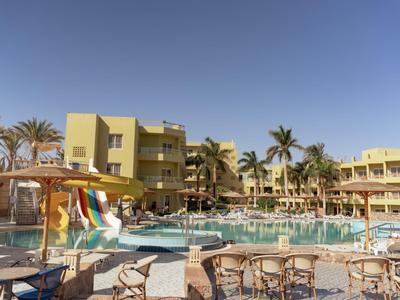 Área de piscina del hotel con toboganes, tumbonas y palmeras bajo un cielo despejado.