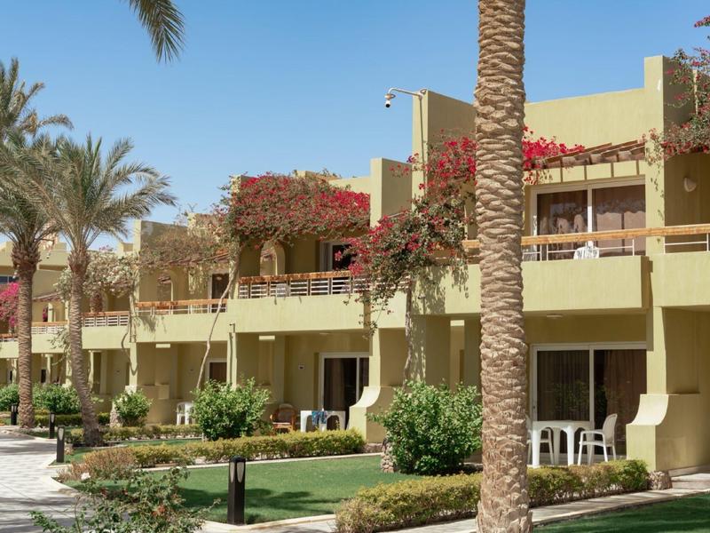 Hotelgebäude mit Balkonen und Palmen in einer sonnigen, tropischen Umgebung