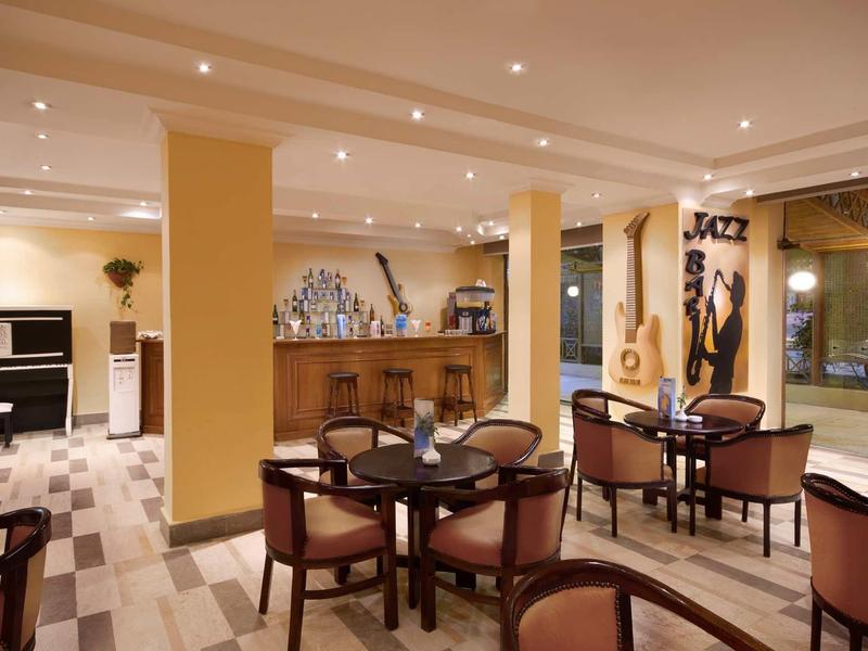 Moderner Gastraum mit runden Tischen, gepolsterten Stühlen und einer Jazz-Dekoration an der Wand.