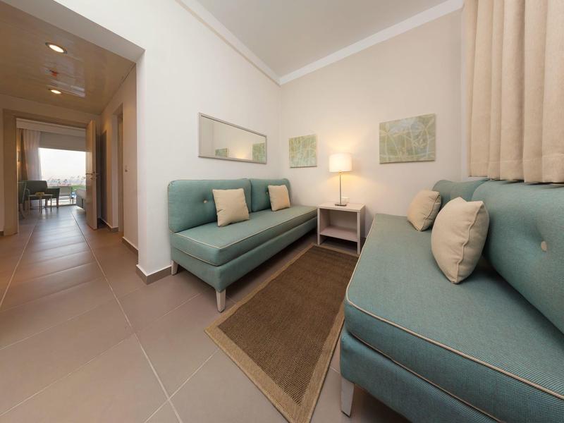 Helles Wohnzimmer mit zwei türkisfarbenen Sofas, hellem Teppich, Wandkunst und Stehlampe.