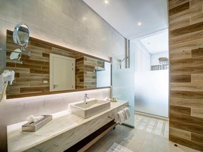 Modernes Badezimmer mit Holzfliesen, großem Spiegel, Waschbecken auf Marmorplatte und Walk-in-Dusche.