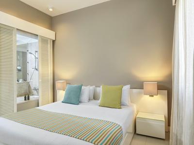 Modernes Hotelzimmer mit großem Bett, zwei Nachttischen und Zugang zum Badezimmer.