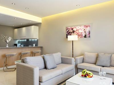 Moderne Hotellounge mit gemütlichen Sofas, Barhockern und Fruchtkorb auf dem Tisch.