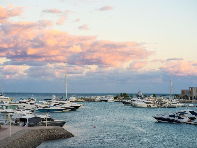 Marina with yachts docked under a colorful sunset sky.