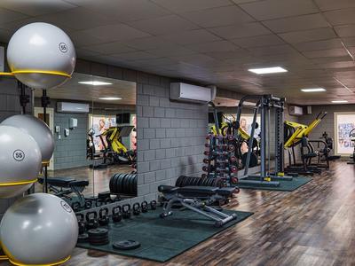 Innenraum eines Fitnessstudios mit Geräten, Hanteln, Gymnastikbällen und Spiegelwand.