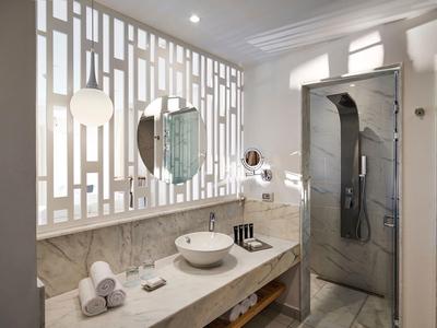 Modernes Badezimmer mit großem Spiegel, weißen Handtüchern und grauer Duschkabine.