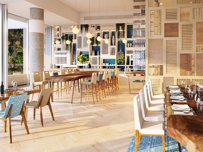 Helles Restaurant mit Holztischen, blauen Stühlen und großen Fenstern zur begrünten Außenseite.