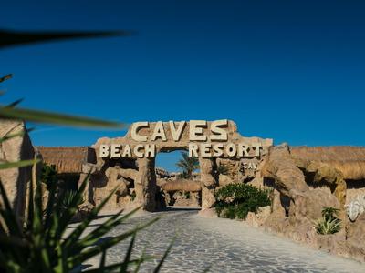 Wejście do Caves Beach Resort z naturalnymi kamiennymi łukami i czystym niebieskim niebem.