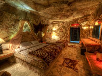 Przytulna sypialnia w jaskini z rustykalnym drewnem i ciepłym oświetleniem.