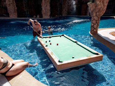 Ludzie grają w bilard na unoszącym się stole w hotelowym basenie.
