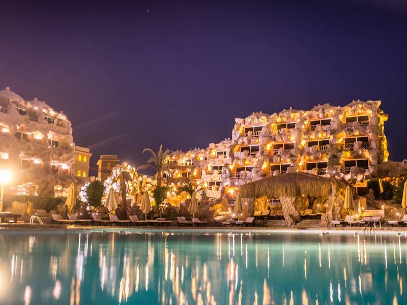 Verlichte hotels bij het zwembad 's nachts weerspiegeld in rustig water