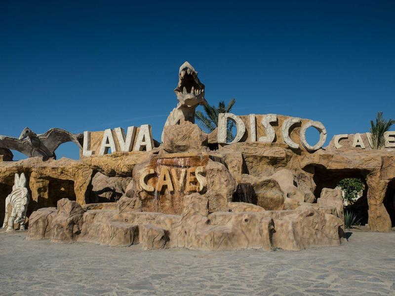 Rotsstructuur met letters 'Lava Disco Caves' onder blauwe lucht