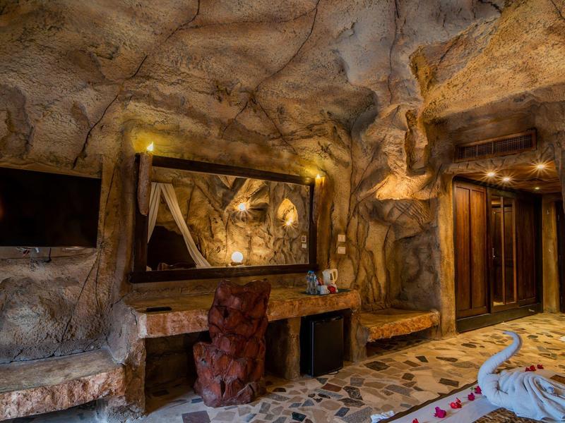 Warme verlichting in een grotachtige hotel lobby met spiegel, tv en decoratieve elementen.