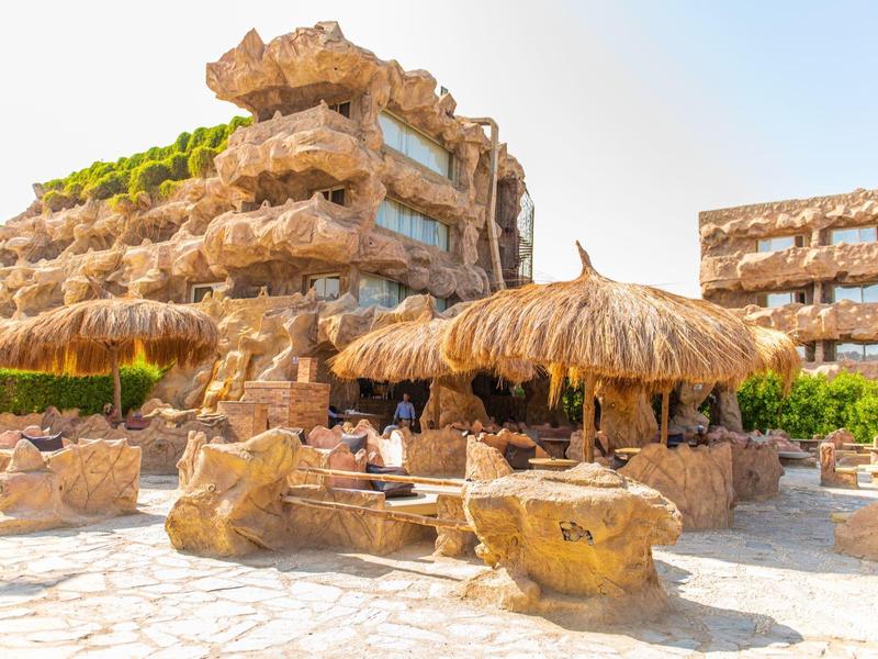 Hotel met rotsachtige architectuur en rieten bar bij zonnig weer