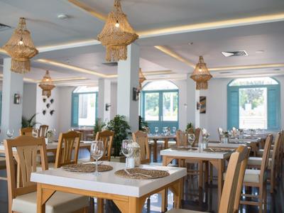 Modernes Restaurant mit Holztischen, Stühlen, großen Fenstern und hängenden Lampen in hellem Raum.