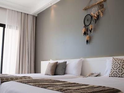 Modernes Schlafzimmer mit grauer Wand, weißem Bett, Kissen und Traumfänger an der Wand.