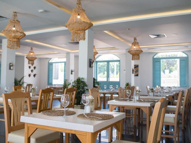 Heller und eleganter Speisesaal mit Holztischen, Stühlen und dekorativen Lampen.