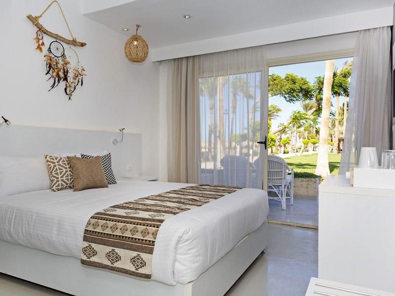 Modernes, helles Schlafzimmer mit Doppelbett und Zugang zum Garten durch große Schiebetüren.