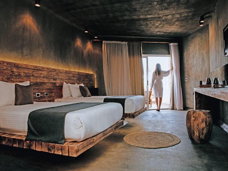 Modern eingerichtetes Schlafzimmer mit zwei Betten und Blick auf einen Balkon.