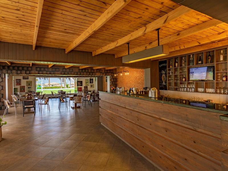 Großer Hotelbar- und Loungebereich mit Holzakzenten und offenem Blick nach draußen.