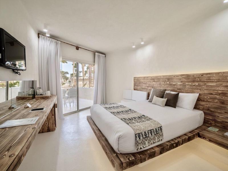 Modernes Schlafzimmer mit Doppelbett, Holzakzentwand, Holzmöbeln und großen Fenstern mit Vorhängen.