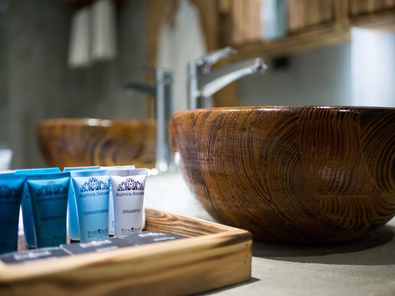 Moderner Waschbereich mit Holzschale und blauen Kosmetikartikeln auf einem Holztablett.