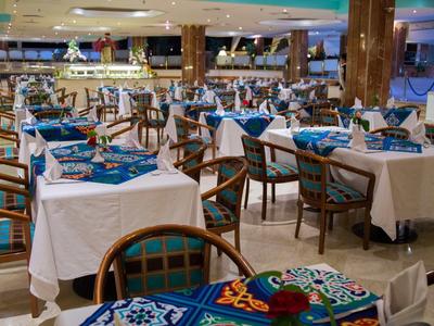 Großes, elegantes Restaurant mit weißen Tischtüchern, blauen Stoffservietten und hölzernen Stühlen.
