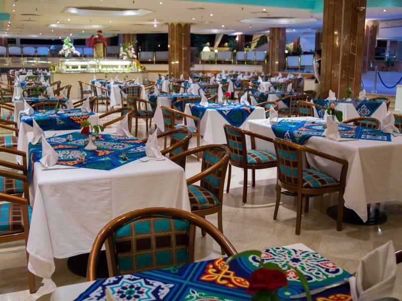 Salle à manger d'hôtel avec tables dressées et chaises en bois.