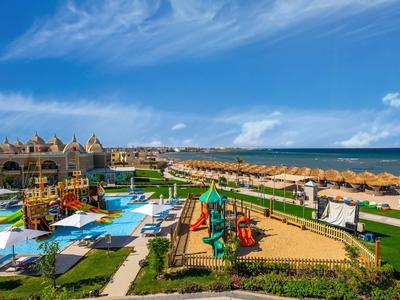 Bunter Kinderspielplatz und Wasserspaßbereich neben Sandstrand und Meer unter blauem Himmel