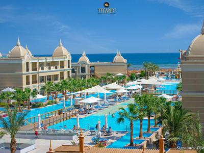 Großes Hotelresort mit mehreren Pools, Palmen und Blick aufs Meer unter blauem Himmel.