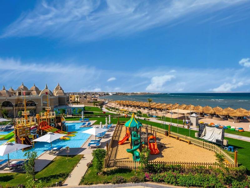 Vue sur une zone de piscine familiale avec toboggans aquatiques et cabanes de plage en bord de mer.