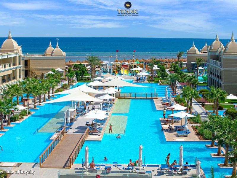 Grand piscine d'hôtel avec transats et vue sur la mer sous un ciel bleu.