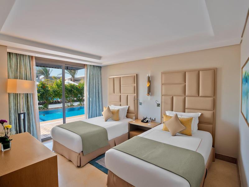 Modern hotel room with two single beds, pool view, and bright interior.