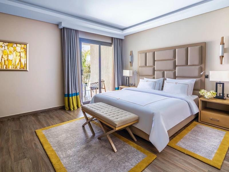 Modern hotel room with double bed, rug, nightstands, and balcony view.