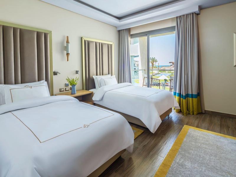 Hotel room with two single beds, modern decor, and a window with outdoor view.