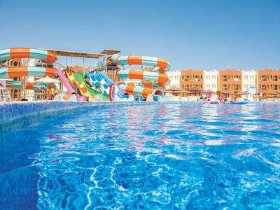 Großer Wasserpark mit blauen Rutschen und klarblauem Pool unter strahlend blauem Himmel.